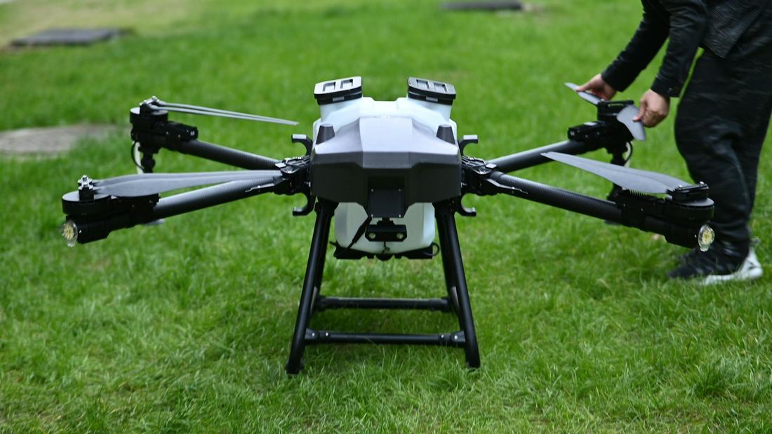 Dron agrícola con estanque de aplicación preparado en terreno