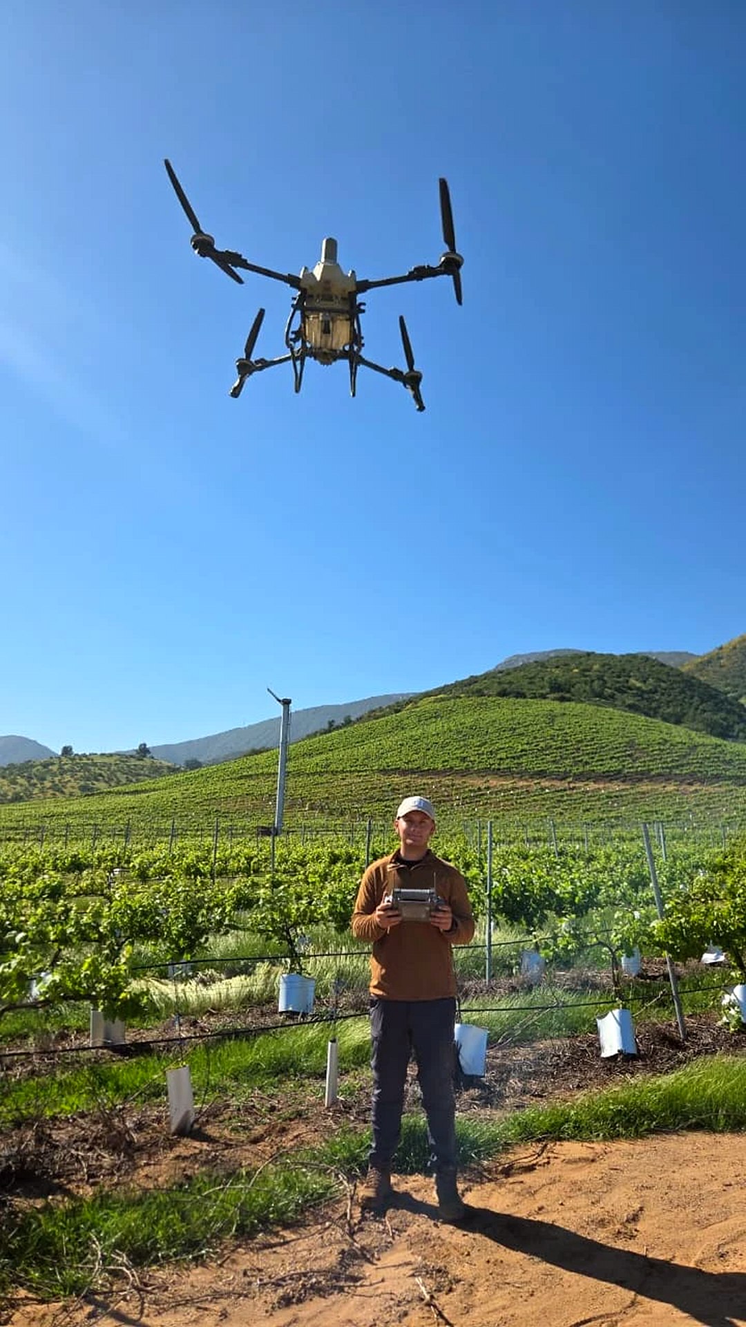 Franco Osorio en un viñedo con el control remoto, con el dron DJI Agras T55 volando sobre él